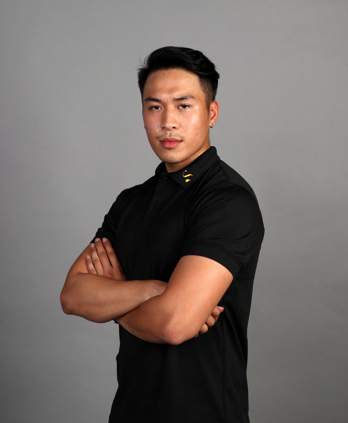 Portrait of Quan Tran, arms crossed, in black and white