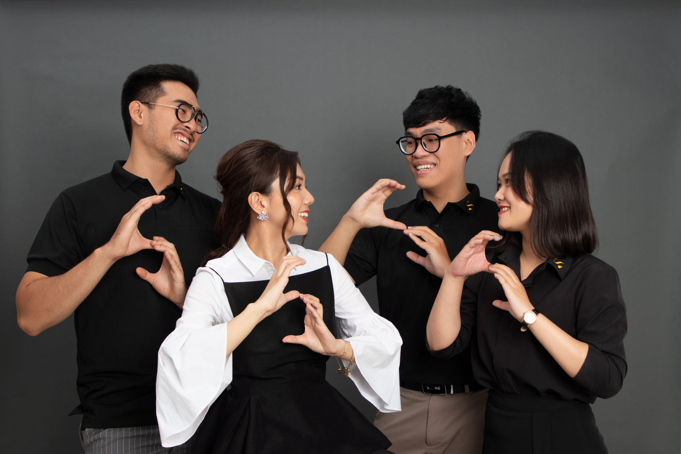 A team of four in black and white outfits posing together against a grey backdrop